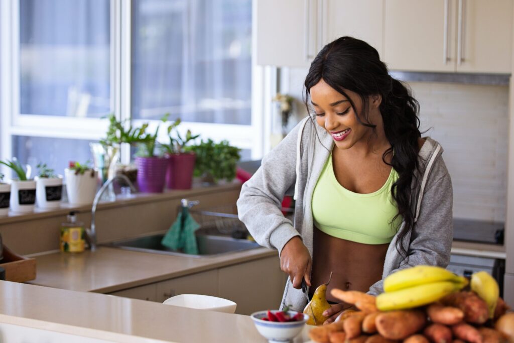 a woman in activewear slicing a pear in her kitchen
